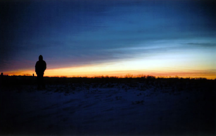 A solitary figure in a snowy field at sunset